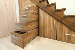 A wooden unseen storage drawers under the stairs