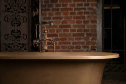 A modern bathroom with brick wall with a rustic bathtub